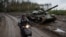 Местный житель едет на скутере мимо подбитого российского танка в Изюме, 14 сентября 2022 года