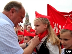 Геннадий Зюганов повязывает красный галстук на шею девочки, в знак принятие в пионерскую молодежную коммунистическую организацию, Красная площадь в Москве 16 мая 2010 года