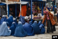 Афганские женщины в бурках сидят вдоль дороги в поисках милостыни на рынке в районе Акча провинции Джаузджан, 3 февраля 2025 года. Фото AFP