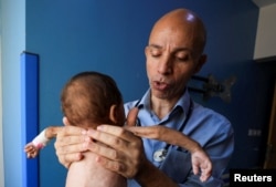 Врач Ахмед Басал обследует ребенка на признаки недоедания в больнице ар-Рантиси в Газе, 7 августа 2025 года